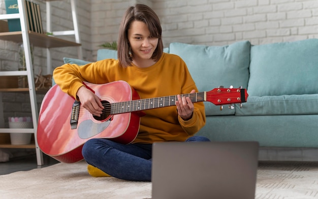 Full shot femme jouant de la guitare à la maison