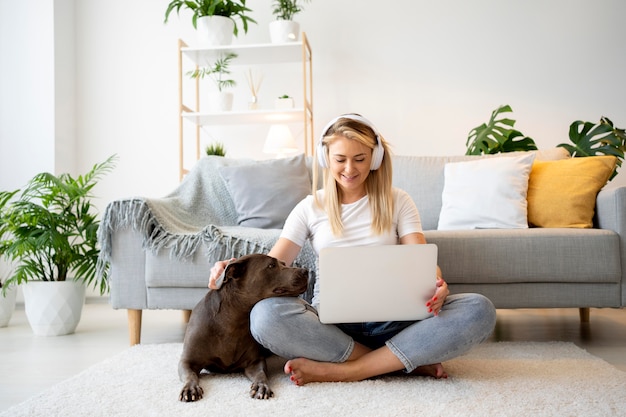 Full shot femme avec ordinateur portable et chien sur marbre