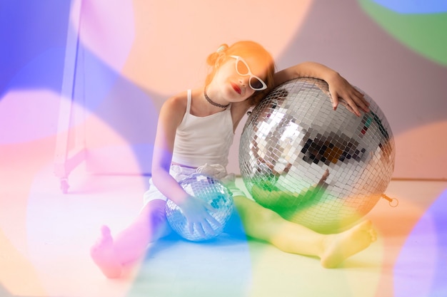 Full shot girl posing avec boule disco et lunettes de soleil