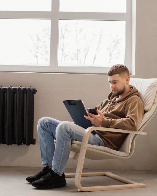 Full shot homme assis sur une chaise