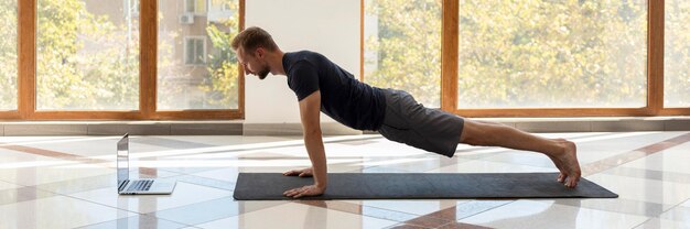 Full shot homme faisant planche à l'intérieur