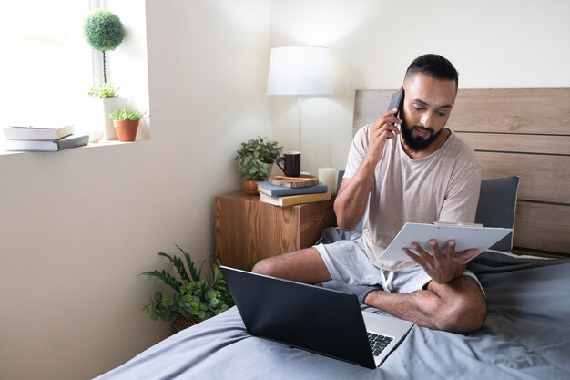 Full shot homme travaillant dans son lit