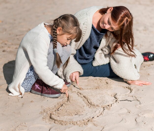 Full shot mère et fille jouant à la plage