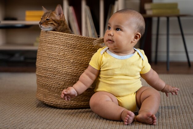 Full shot smiley bébé et chat dans le panier