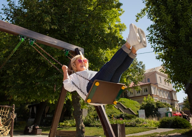 Full shot smiley senior woman on swing