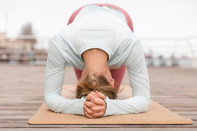 Full shot woman doing yoga sur tapis