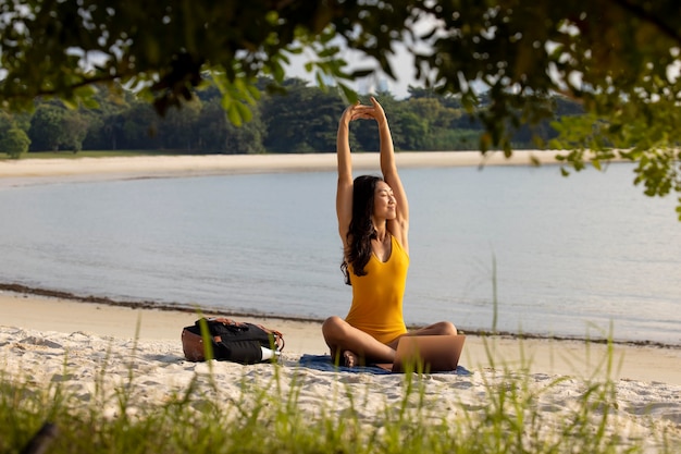 Photo gratuite full shot woman stretching at beach