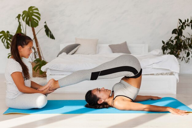 Full shot woman stretching sur tapis de yoga