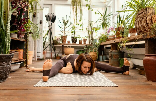 Full shot woman stretching sur tapis