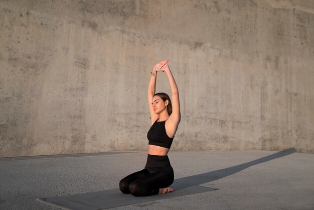 Full shot woman stretching sur tapis