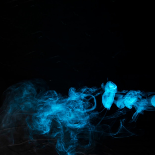 La fumée bleue se propage sur un fond sombre