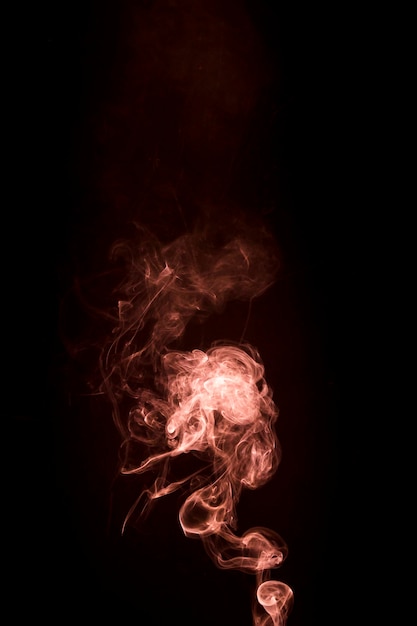 Photo gratuite une fumée orange qui monte sur fond noir