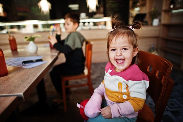 Funny baby girl sitting in cafe et rit