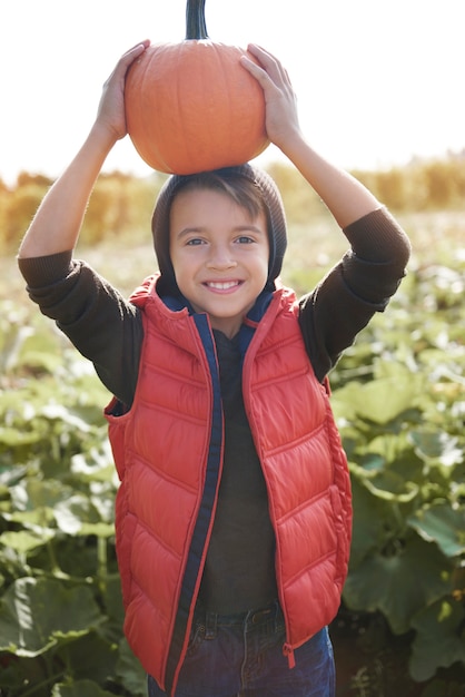 Photo gratuite funny boy holding pumpkin sur le terrain