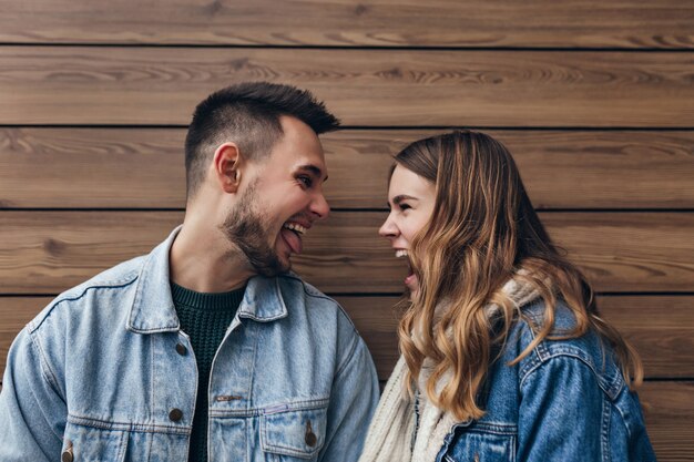 Funny couple européen s'amuser sur un mur en bois. Photo intérieure d'une femme blonde bouclée se détendre avec son petit ami.