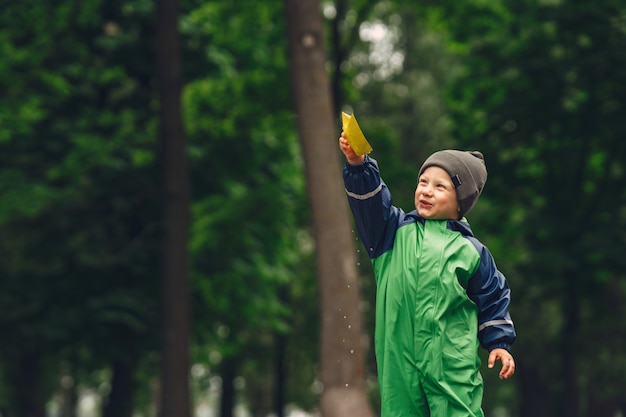 Photo gratuite funny kid en bottes de pluie jouant dans un parc de pluie