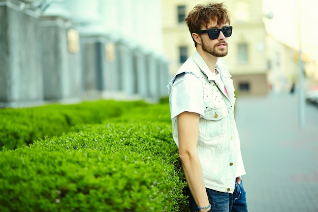 Funny smiling hipster bel homme beau en tissu d'été élégant dans la rue en lunettes de soleil