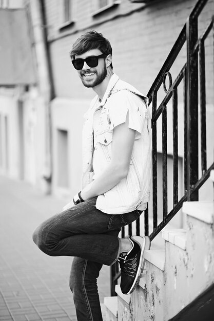 Funny smiling hipster bel homme beau en tissu d'été élégant dans la rue en lunettes de soleil