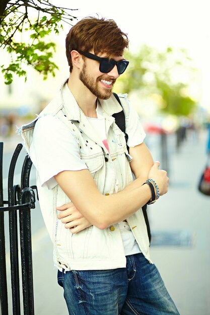Funny smiling hipster bel homme en tissu d'été élégant dans la rue en lunettes de soleil