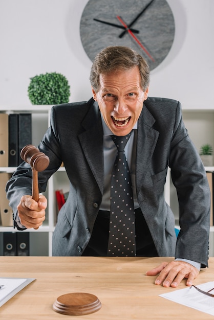 Photo gratuite furieux avocat mûr donnant le verdict en frappant le maillet au bureau