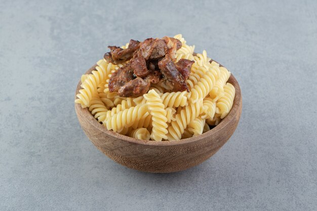 Fusilli et poulet frit dans un bol en bois.