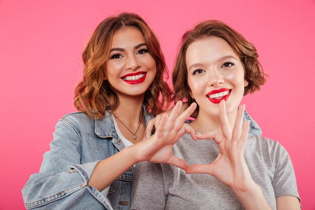 Gai deux femmes étreignant montrant le geste d'amour du cœur.