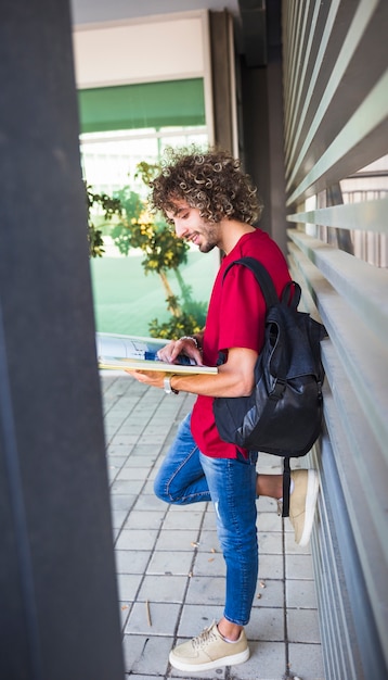 Photo gratuite gai gai avec livre s'appuyant sur le mur