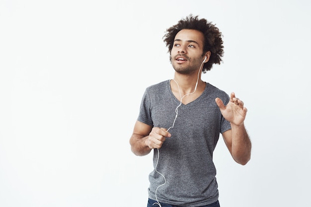 Gai homme africain, écouter de la musique dans les écouteurs, danser, chanter.