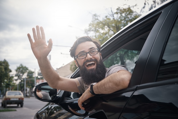 Photo gratuite gai homme agitant en conduisant une voiture