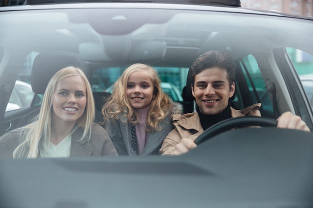 Photo gratuite gai homme assis dans la voiture avec sa femme et sa fille