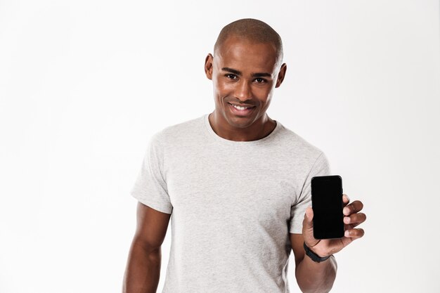Gai jeune homme africain montrant l'affichage du téléphone mobile.