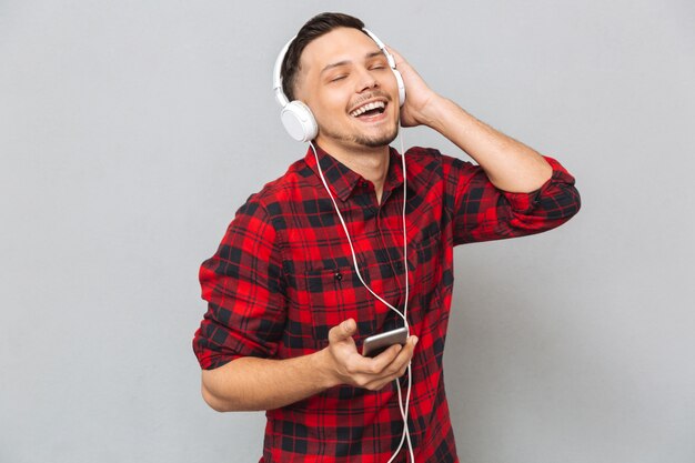 Gai jeune homme écoutant de la musique avec des écouteurs.