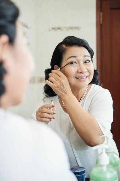 Gaie, femme asiatique senior, mettre, mascara, sur, cils, devant, miroir