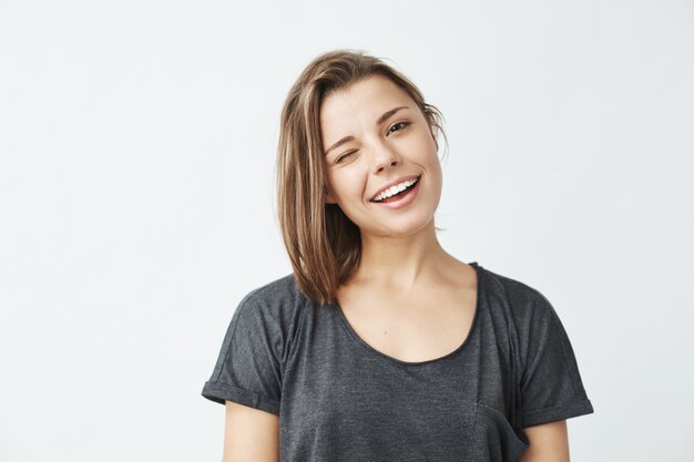 Gaie jeune belle fille souriante un clin de œil.