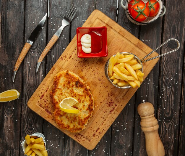 galettes de poitrine de poulet garnies de citron, servies avec frites, mayonnaise et ketchup