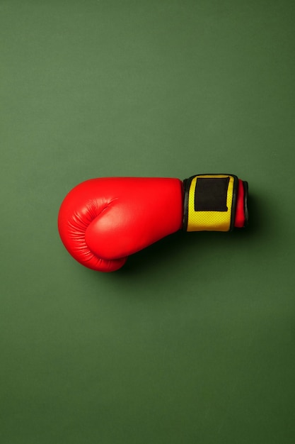 Gant de boxe rouge et jaune vif. Équipement de sport professionnel isolé sur fond vert studio. Concept de sport, activité, mouvement, mode de vie sain, bien-être. Couleurs modernes.