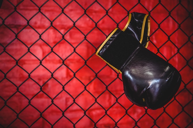 Photo gratuite gant de boxe suspendu à une clôture en treillis métallique