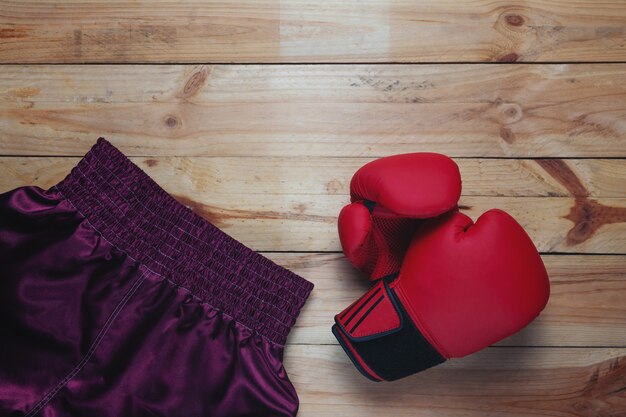 Gant en cuir rouge et pantalon de boxe sur une table en bois