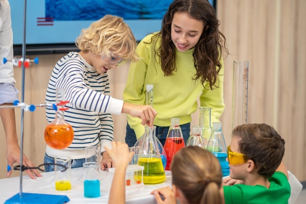 Photo gratuite garçon abaissant la pipette dans la fiole et les enfants regardant