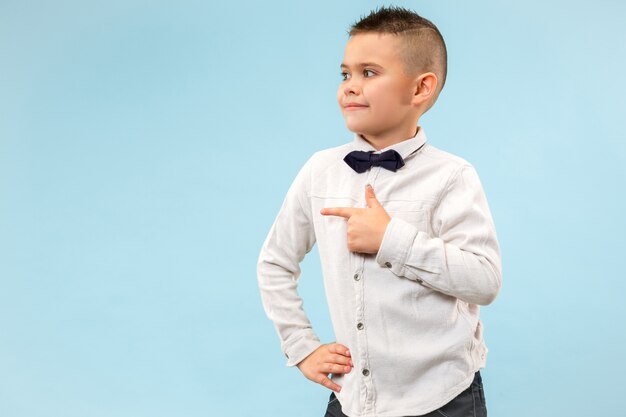 Le garçon adolescent heureux debout et souriant sur fond bleu.