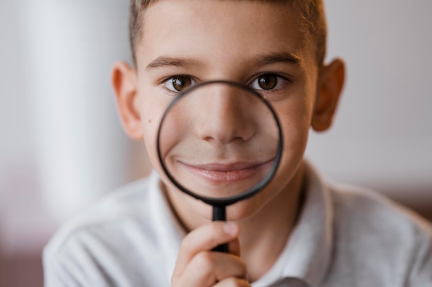 Garçon à l'aide d'une loupe en classe