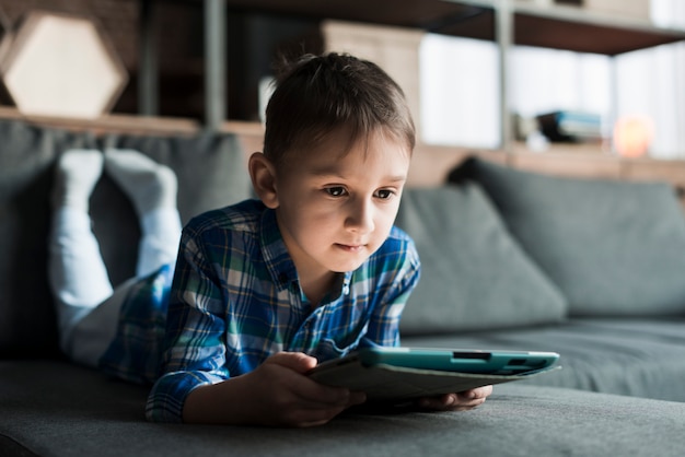 Garçon allongé sur le canapé avec tablette