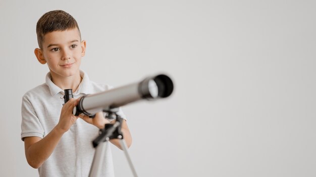 Garçon apprenant à utiliser un télescope avec copie espace