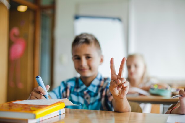 Garçon assis au bureau d&#39;école