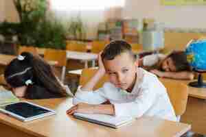 Photo gratuite garçon assis en classe en détournant les yeux