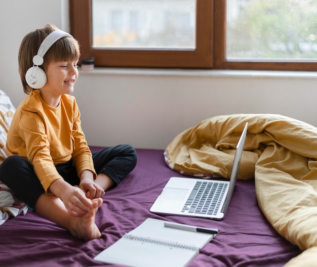 Garçon assis dans son lit et apprenant tout en portant un casque