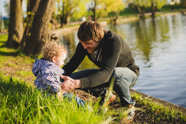 Garçon assis sur l&#39;herbe avec son père