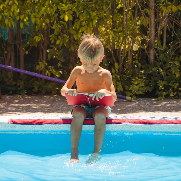 Photo gratuite garçon assis près de la piscine