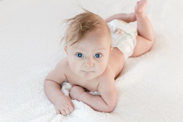 Garcon Blond De Cinq Mois Aux Yeux Bleus Se Trouve Sur Le Ventre Photo Premium