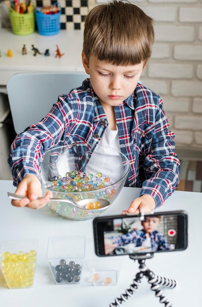 Garçon avec des boules d'hydrogel dans un bol et un téléphone